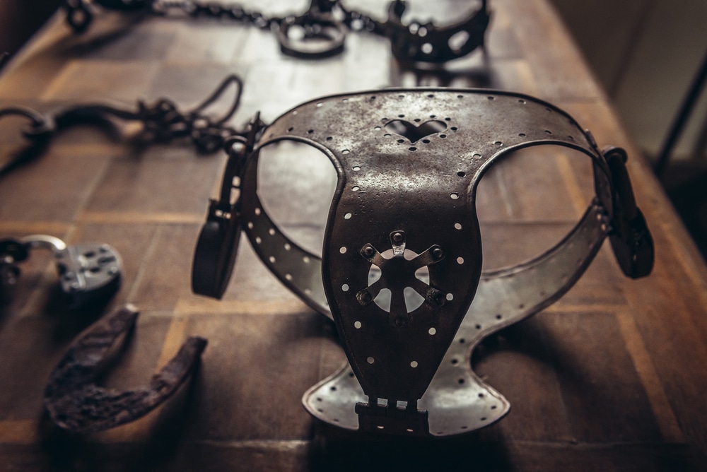 Close-up of an antique metal chastity belt on a wooden table during a BDSM-themed photoshoot
