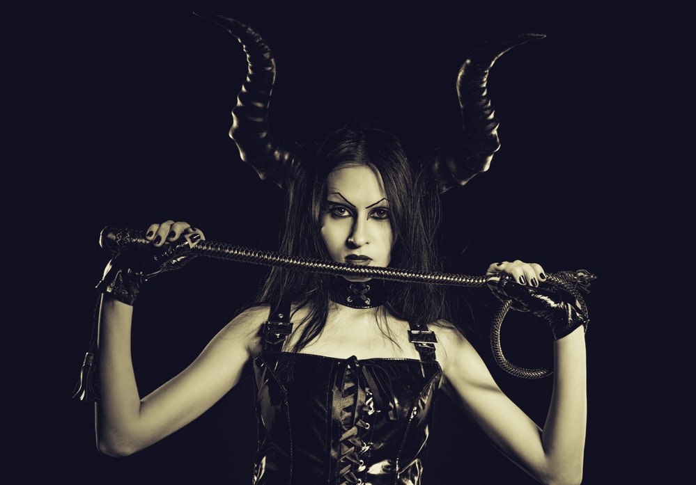 Woman in black leather costume with horns holding a whip, symbolising succubus roleplay and dark fantasy in London