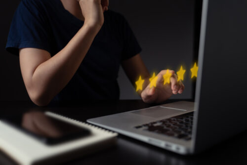 Person leaving a five-star review on a laptop, symbolising feedback and ratings for London escort services