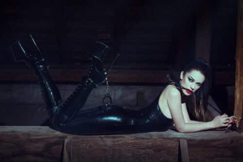 GFE Escort in Mayfair in black latex attire posing with a whip, representing the confident and empowered image often associated with professional escort agencies in London