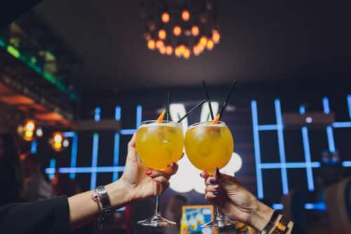 Two women raising cocktails in a stylish London bar during an evening out
