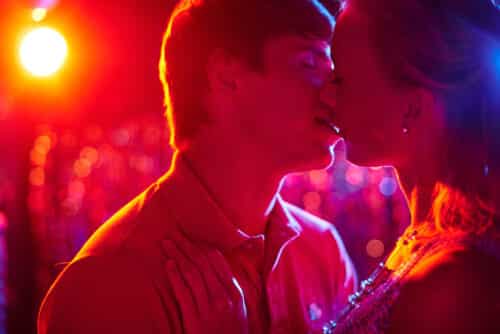 Couple sharing an intimate moment under neon lights in a London nightclub