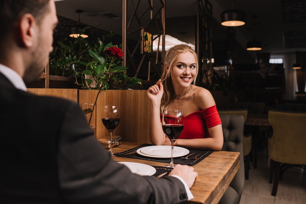 Elegant blonde woman in a red dress smiling during a dinner date at a London restaurant